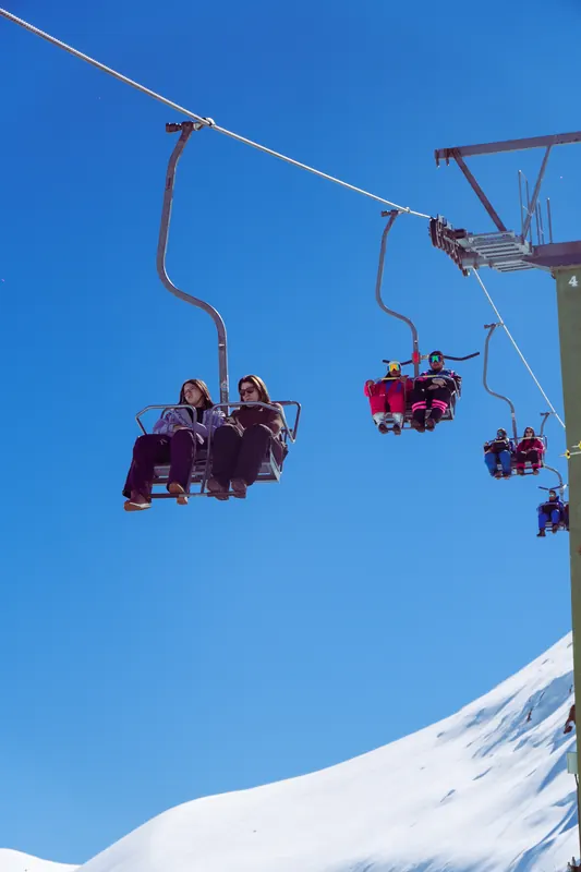 Chairlift with skiers against a deep blue sky